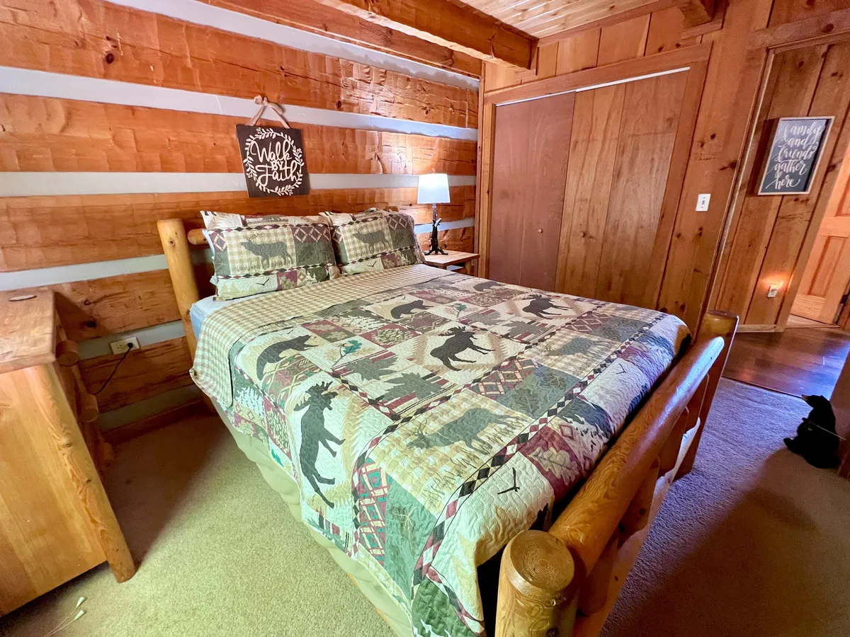 A cozy bedroom with a patterned quilt on the bed, wooden accents, and a softly glowing bedside lamp. The setup provides a restful retreat after a day spent exploring the nearby national park.